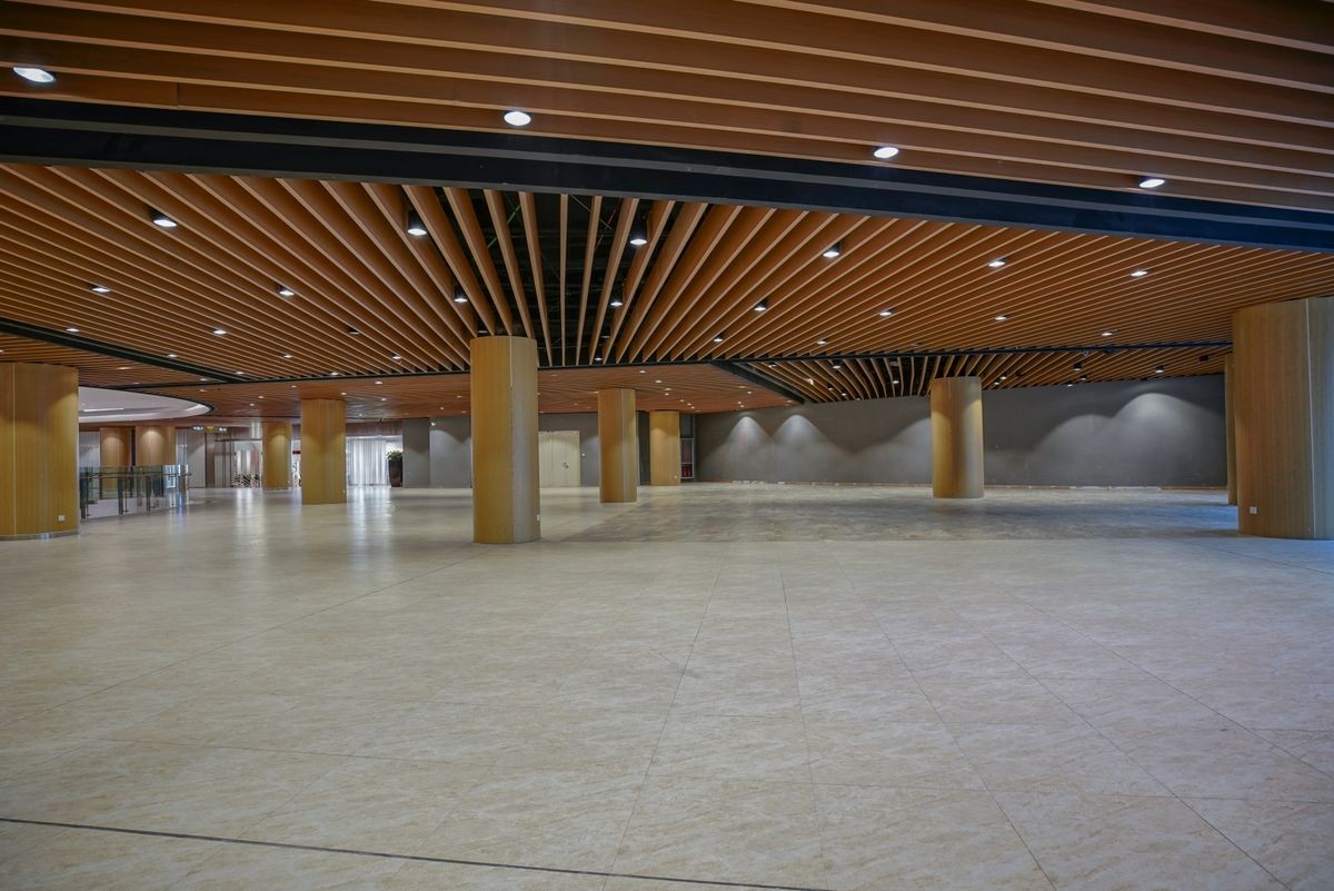 Empty commercial space, with marble floors and celing of wooden partitions.